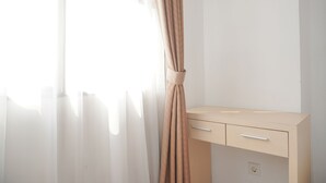 Ein Zimmer mit einem hellen Holztisch, einer weißen Wand und durchsichtigen Vorhängen.