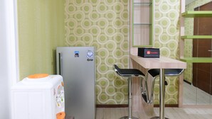 Une cuisine compacte équipée d’un réfrigérateur, de deux tabourets de bar et d’une petite table.
