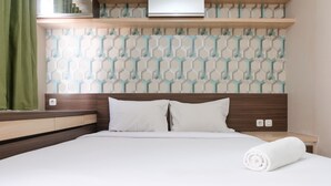 Un lit bien fait, avec du linge de lit blanc et des oreillers, une tête de lit en bois et un mur à motifs derrière.
