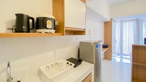 A modern kitchen with a stainless steel sink, a kettle, a coffee maker, and a refrigerator. - Warm And Simply Look Studio Apartment At Tokyo Riverside Pik 2 (Teluknaga)