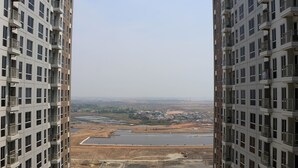 A high-rise building with multiple balconies and a view of a construction site with a large water body and surrounding landscape. - Warm And Simply Look Studio Apartment At Tokyo Riverside Pik 2 (Teluknaga)