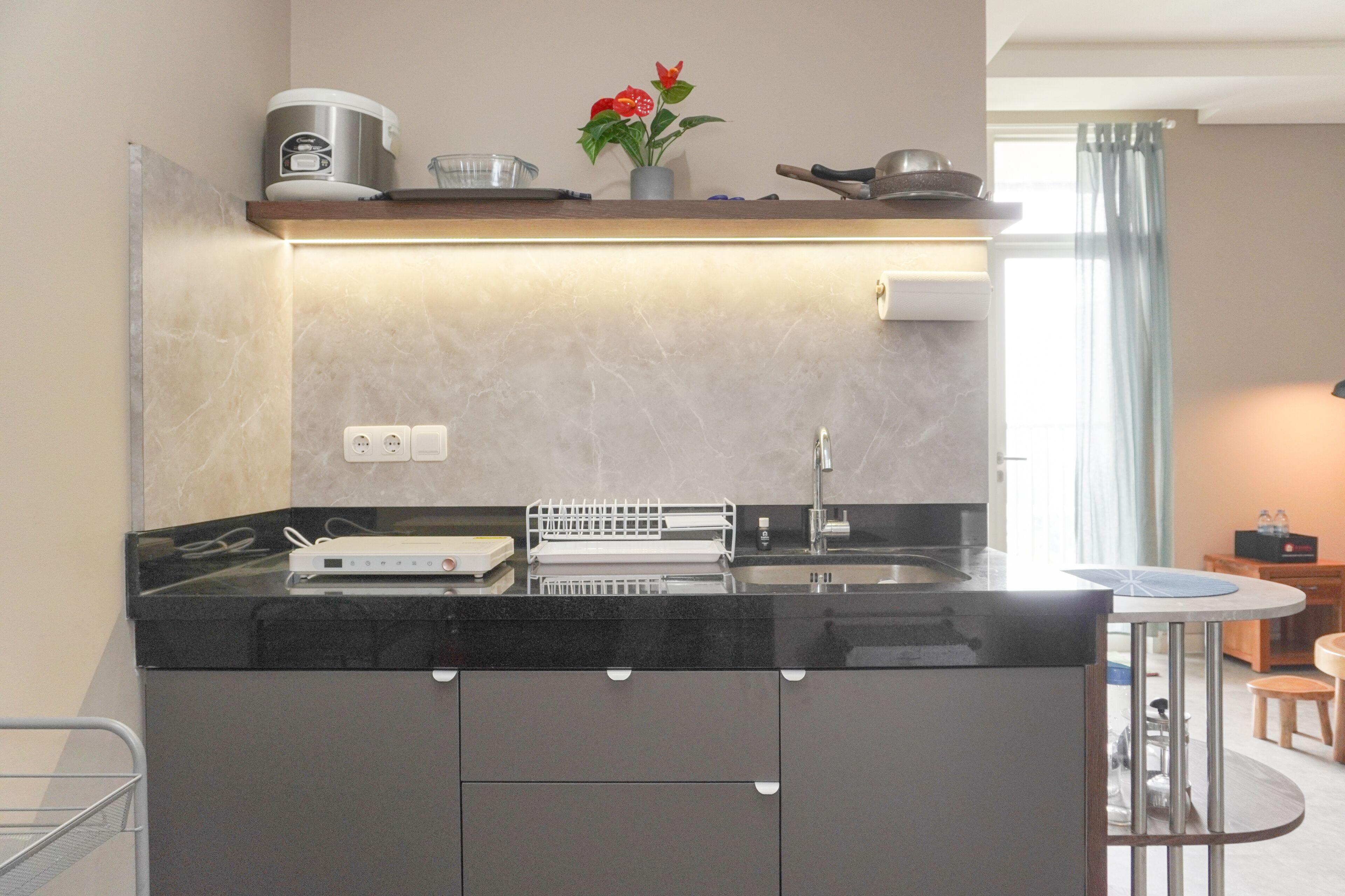 A modern kitchen with a black countertop, a built-in oven, a coffee maker, and a small potted plant.