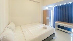 A hotel room with a bed, a wooden nightstand, a wardrobe, and a window with curtains. - Homey And Comfortable 2Br At Tokyo Riverside Pik 2 Apartment (Jakarta)