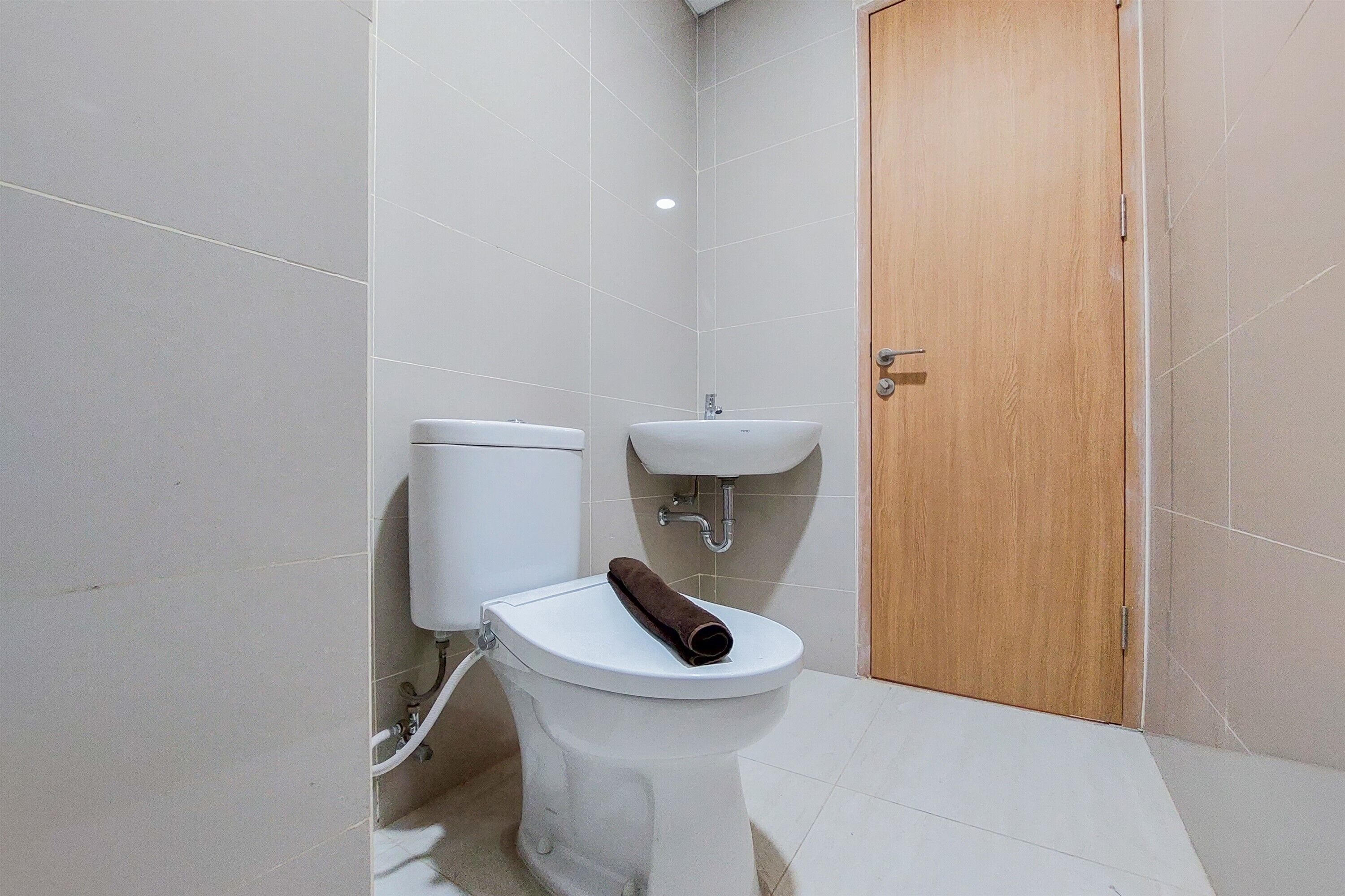 Une petite salle de bain avec des toilettes, un lavabo et une porte en bois.