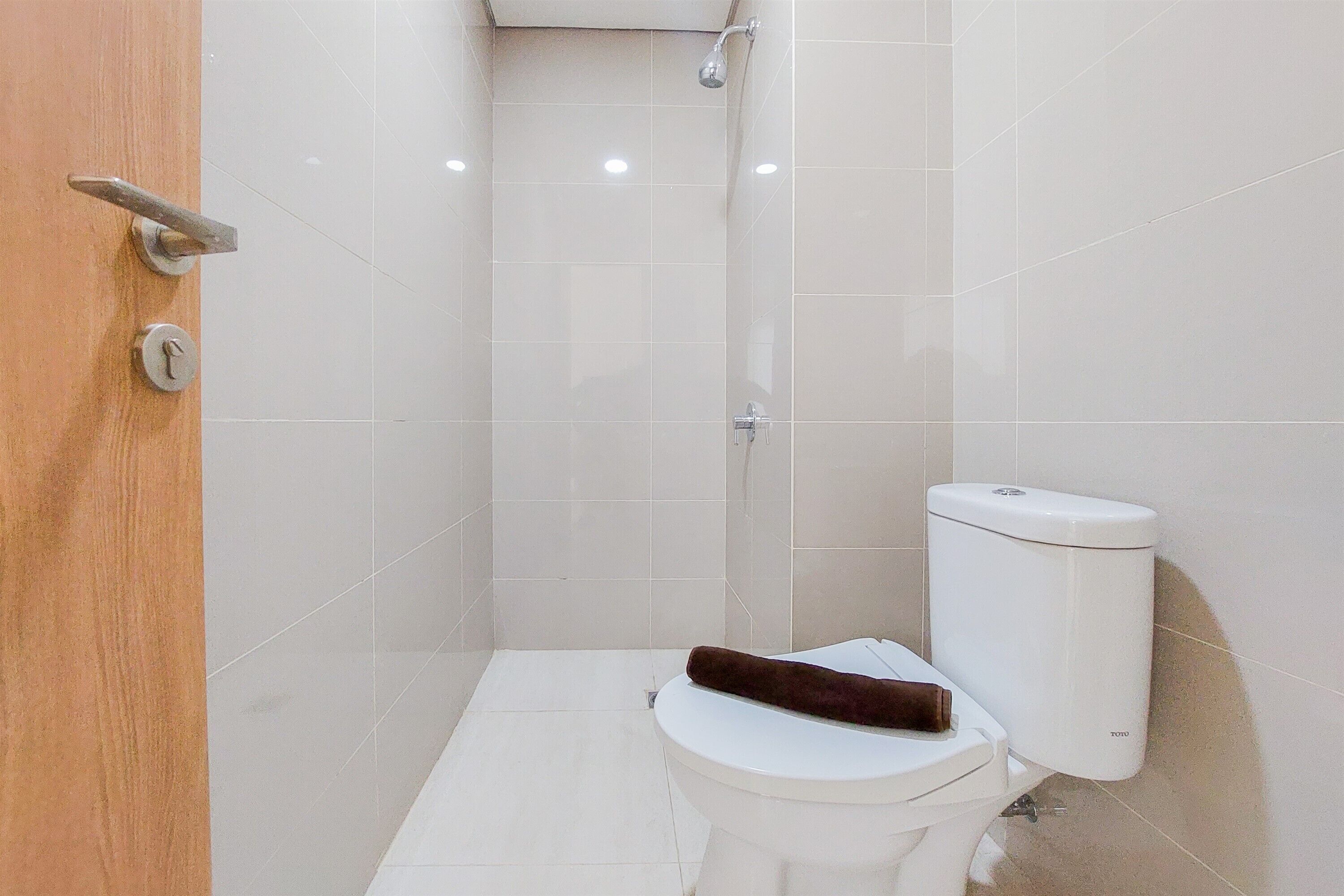 Un bagno piccolo e moderno con un WC bianco, una doccia e una porta in legno.