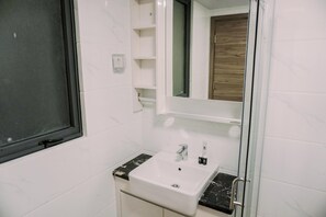 A bathroom with a white sink, a mirror, and a glass shower enclosure. - Homey And Spacious 3Br At Sky House Bsd Apartment (Pagedangan)