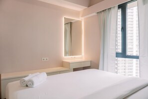 A hotel room with a bed, a bedside table, a mirror, and a window with curtains. - Homey And Spacious 3Br At Sky House Bsd Apartment (Pagedangan)