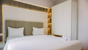 Ein ordentlich gemachtes Bett mit weißen Leinen und Kissen, ein hölzernes Kopfteil und ein Nachttisch mit einer Lampe.