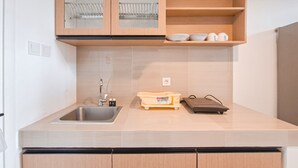 A modern kitchen with a sink, wooden cabinets, and a countertop. - Cozy Stay And Comfy Studio Loft Kingland Avenue Apartment (South Tangerang)