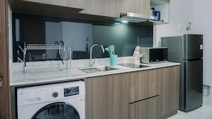 A modern kitchen with wooden cabinets, a stainless steel refrigerator, a microwave, and a dishwasher. - Wonderful And Homey 1Br The Smith Alam Sutera Apartment (Tangerang)