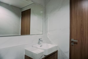 A bathroom with a white sink, a mirror, and a wooden door.
