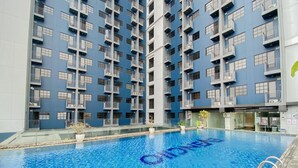 A modern building with a pool area. - Minimalist 1Br With Extra Room At Evenciio Margonda Apartment (Depok)