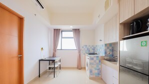 A compact kitchen with a refrigerator, washing machine, and a small dining table. - Minimalist 1Br With Extra Room At Evenciio Margonda Apartment (Depok)
