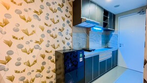 A modern kitchen with a patterned wallpaper, a built-in dishwasher, and a microwave. - Simple And Cozy Studio Tamansari Skylounge Makassar Apartment (Makassar)