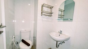 A bathroom with a toilet, sink, and a towel rack. - Simple And Cozy Studio Tamansari Skylounge Makassar Apartment (Makassar)