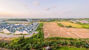 A residential area with modern houses, a road, and agricultural fields. - Simple And Cozy Studio Tamansari Skylounge Makassar Apartment (Makassar)