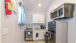 A compact kitchen with white cabinets, a stove, a microwave, and a refrigerator. - Modern, stylish, peaceful apartment with a great view! (Buckleys)