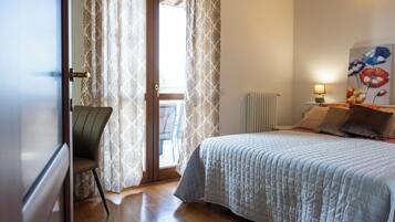 A bedroom with a bed, a chair, a radiator, and a painting on the wall.