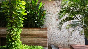 A garden with a brick planter, a stone wall, and a variety of green plants. - Wynwood Eslava in Cartagena (Cartagena)