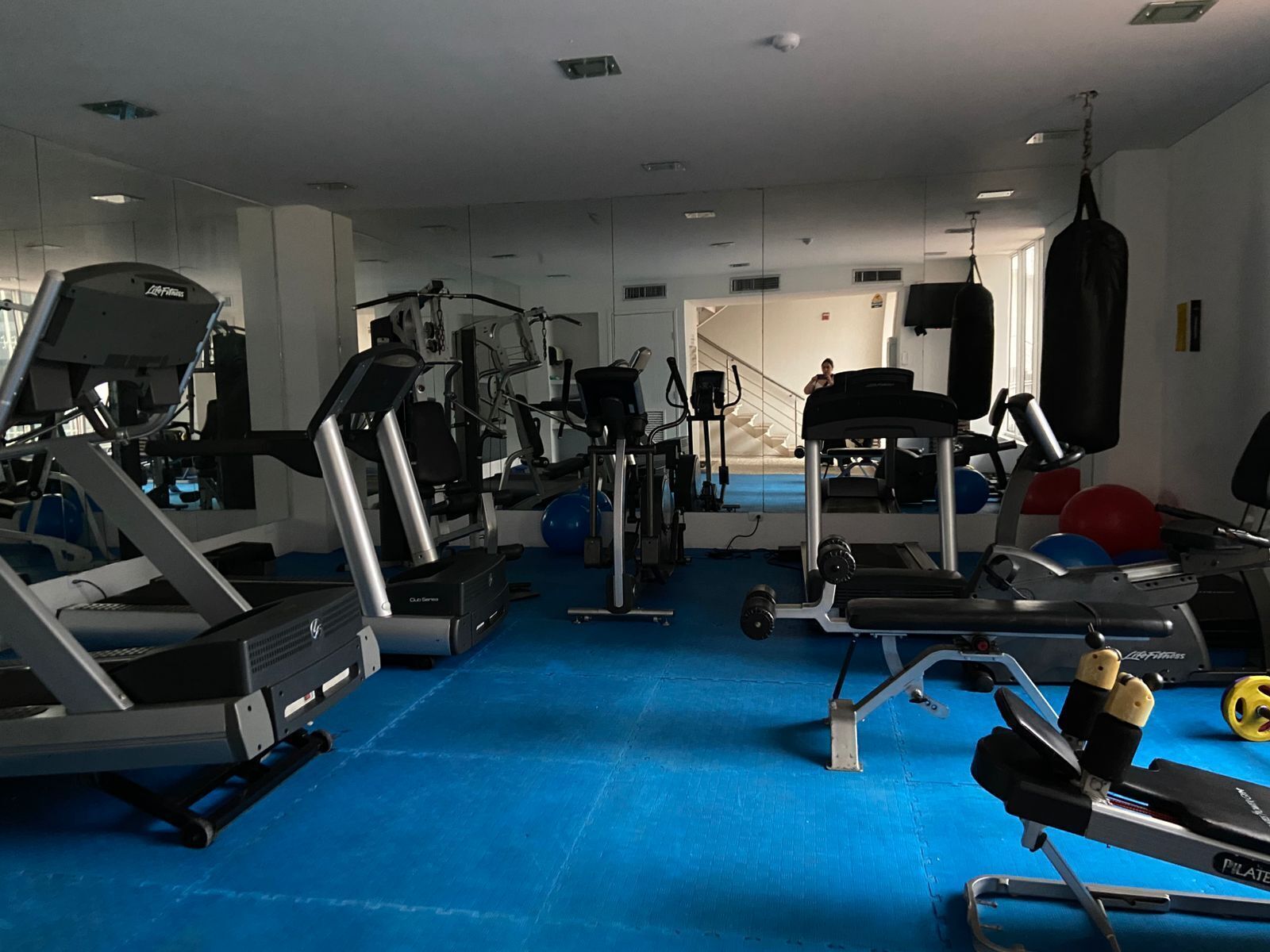 A gym with various exercise equipment, including treadmills, weight machines, and a punching bag.