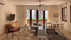 A modern living room with a TV, sofa, dining table, chairs, and a kitchen area with a sink and stove. - Wynwood Eslava in Cartagena (Cartagena)