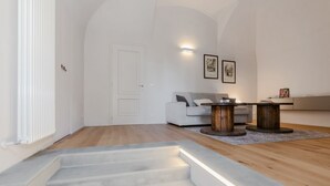 A modern living room with a staircase, a white sofa, a coffee table, and a wooden side table.