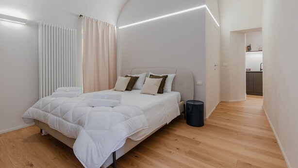 A modern bedroom with a bed, bedside table, and a small trash bin.