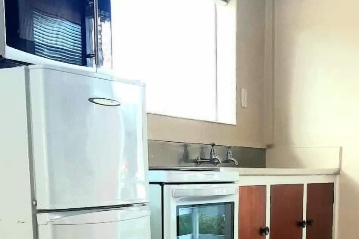 A compact kitchen with a refrigerator, oven, and cabinets.