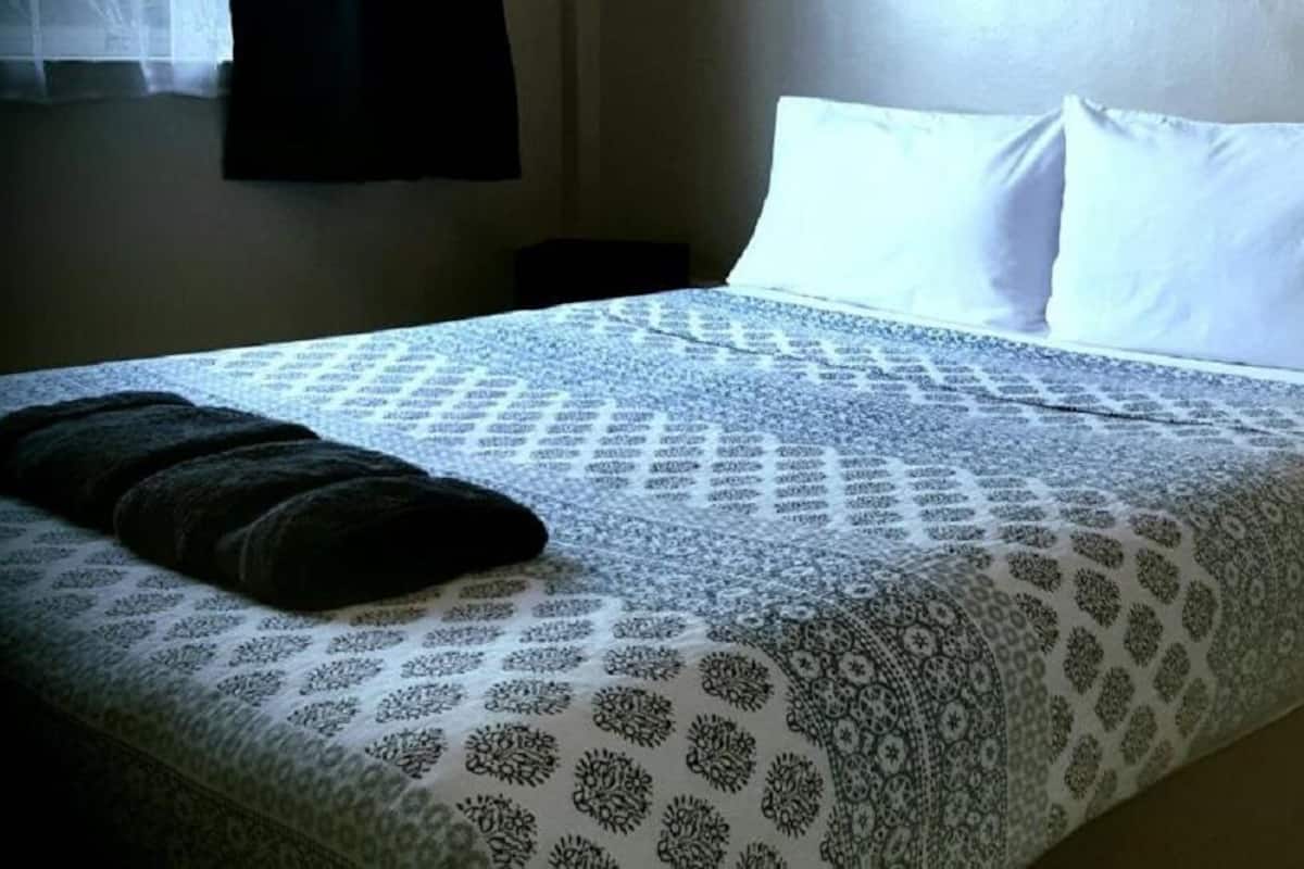 A neatly made bed with patterned bedding and a dark-colored pillow.
