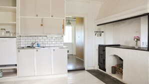 Una cocina con armarios blancos, encimera negra y chimenea.