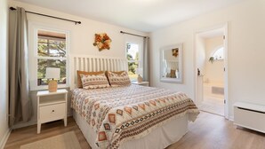 A bedroom with a large bed, a nightstand, a window with curtains, and a door leading to another room. - Meadow Farm in Holly Springs, NC (Holly Springs)