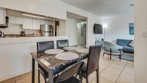 A modern kitchen with white cabinets, a marble countertop, and a dining area with a table and chairs.