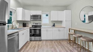 Une cuisine moderne avec des meubles blancs, des appareils en acier inoxydable et un plancher en bois.