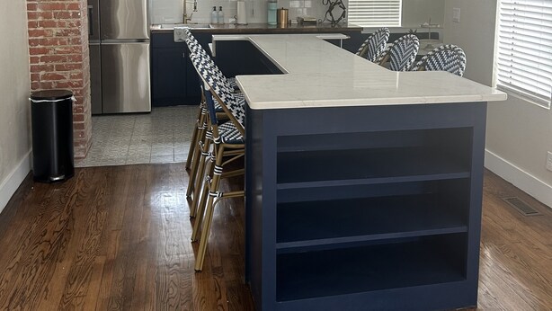 A modern kitchen with a central island, stainless steel appliances, and white cabinetry.