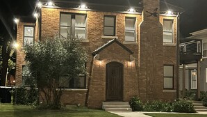 A two-story brick house with a front entrance, a chimney, and a well-maintained lawn.