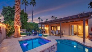 A swimming pool with a stone border, a covered patio area, and a view of a house with a pergola. - Sonrisa Sunshine-Pool,Spa,Walk to BNP 3BD #066685 (La Quinta)