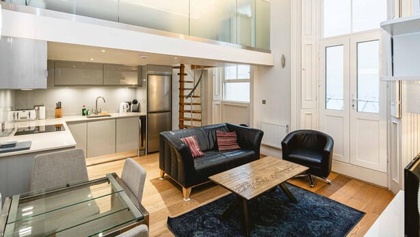 Un appartement moderne comprenant une cuisine, un coin repas et un salon avec un canapé et une table basse.