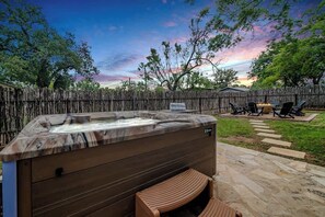 En baghave med jacuzzi, fliseterrasse, træterrasse og træhegn.