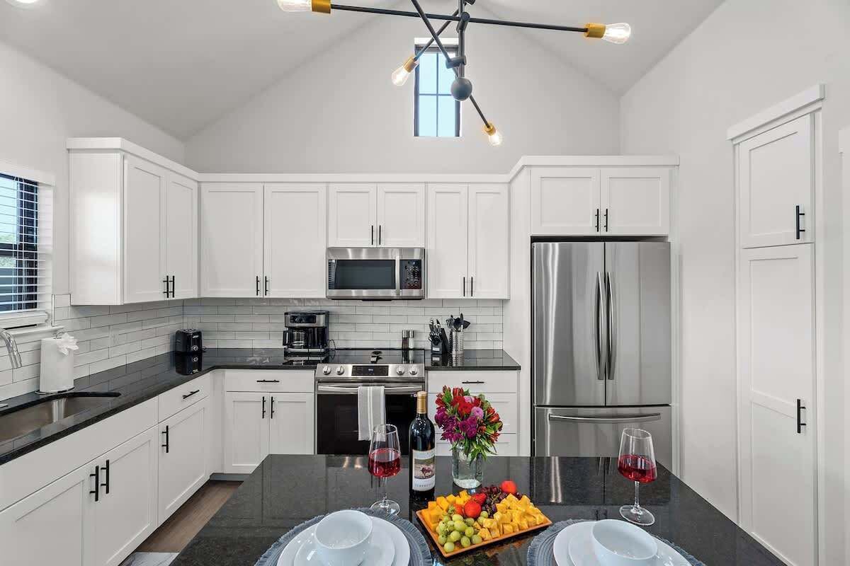A modern kitchen with white cabinets, stainless steel appliances, and a black countertop.