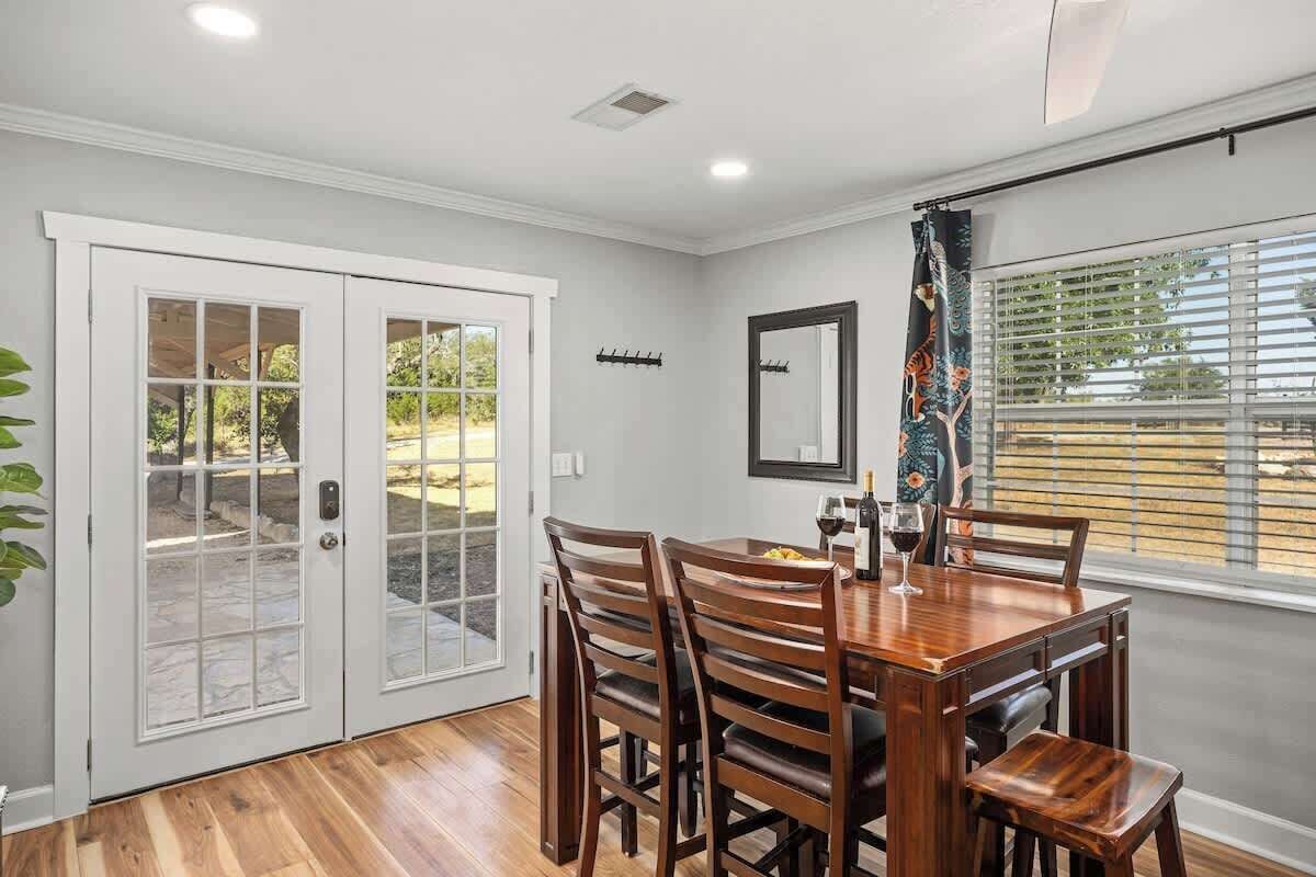 A dining area with a wooden table and chairs, a window with blinds, and a door with glass panels.