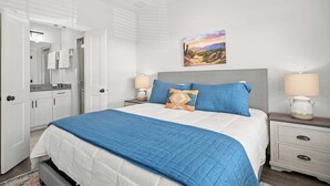 A bedroom with a bed, two bedside tables, a nightstand, a mirror, and a painting on the wall. - Lucille's Abode With Hot Tub (Fredericksburg)