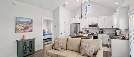 A modern kitchen with white cabinets, a stainless steel refrigerator, and a microwave.