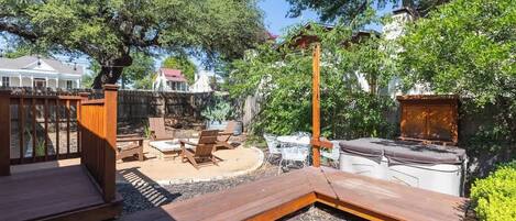 A wooden deck with outdoor furniture, a barbecue grill, and a hot tub.