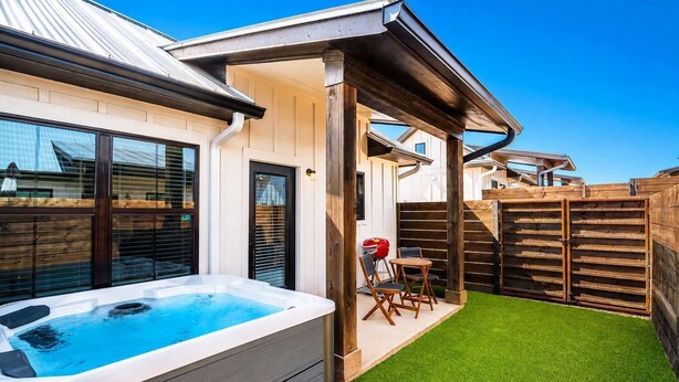 Ein Garten mit Whirlpool, einer Holzterrasse und einem eingezäunten Bereich.