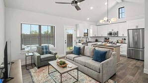 A spacious living area with a gray sofa, a coffee table, and a TV. - Fred's Joint With Hot Tub (Fredericksburg)