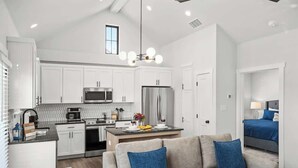 A modern kitchen with white cabinets, stainless steel appliances, and a central island. - Fred's Joint With Hot Tub (Fredericksburg)