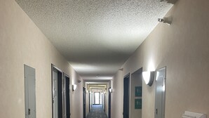 A long, narrow hotel corridor with doors on both sides, a patterned carpet, and light fixtures on the walls. - Hotel Yuma (Yuma)