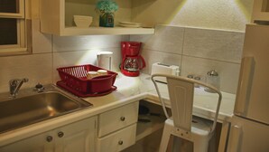Een keuken met een roestvrijstalen spoelbak, een rode koffiezetapparaat en witte kastjes.