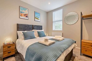 A bedroom with a bed, bedside tables, a window, and wall art.