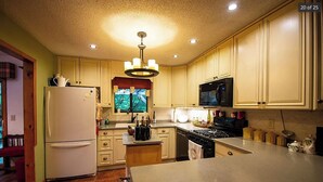 A kitchen with a refrigerator, stove, microwave, and wooden cabinets. - Murphy Mountain House - Creeks, Firepits & High Speed Internet! (Murphy)